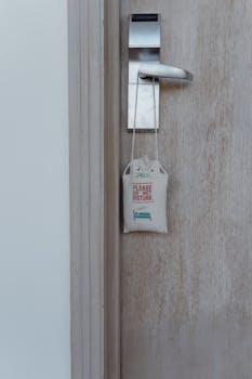 Close-up of a hotel room door with a do not disturb sign hanging on the handle.