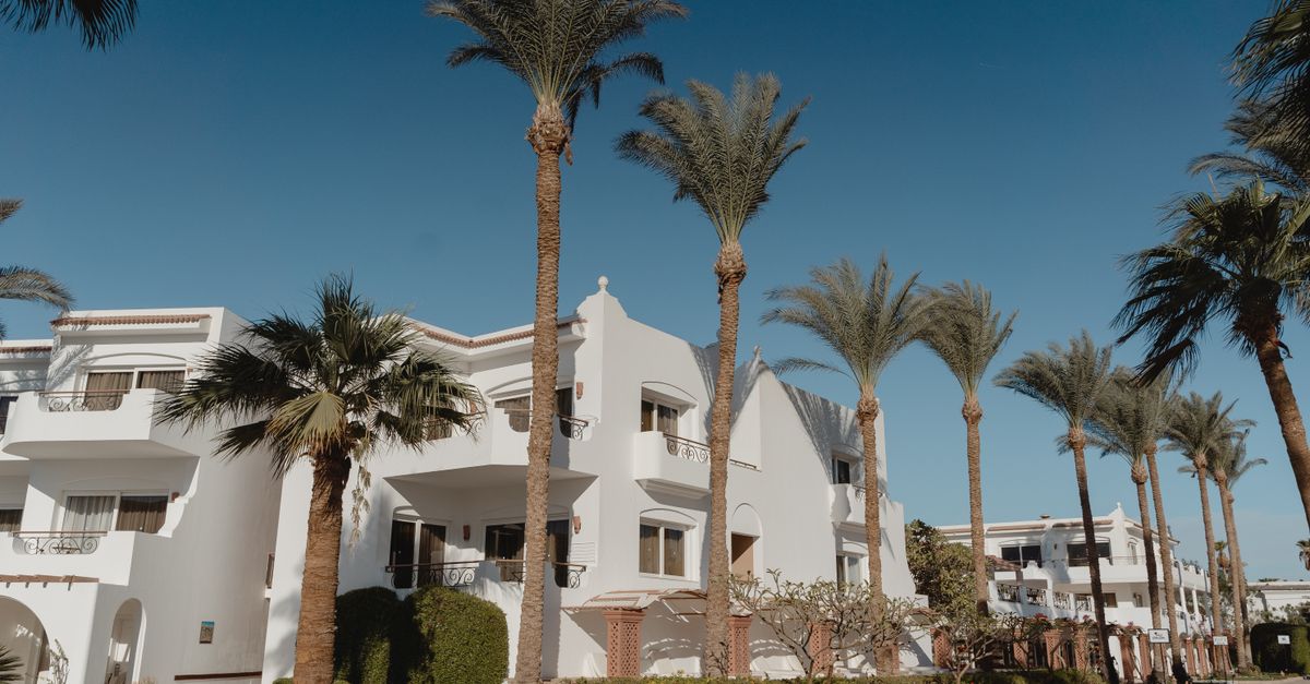 Stunning view of white Mediterranean-style villas lined with tall palm trees under a clear blue sky.