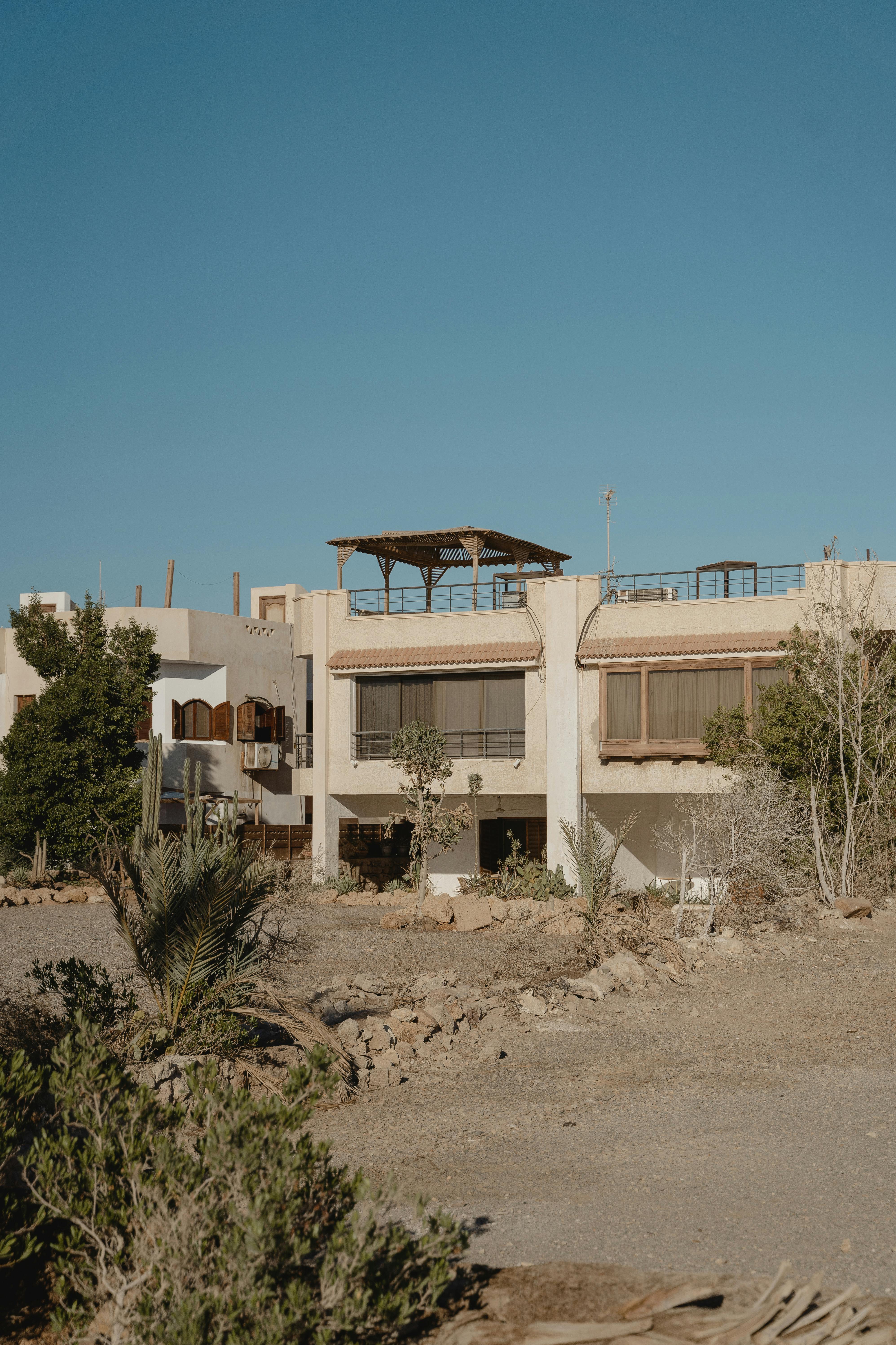 A deserted building in a desert setting with a clear blue sky, showcasing architecture and sparse vegetation.