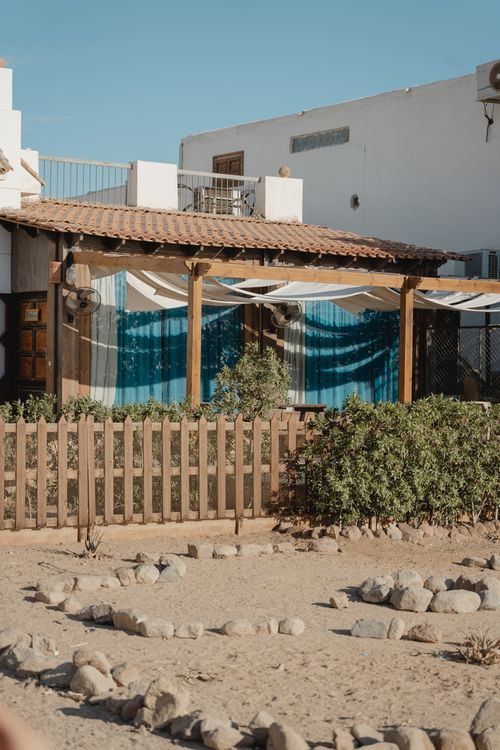 Free Charming Mediterranean house with wooden fence and plants under clear blue sky. Stock Photo