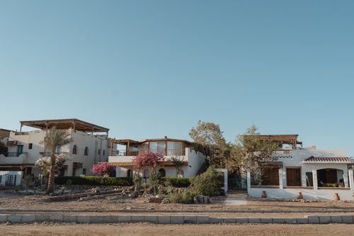 Free Mediterranean-style villas with pink bougainvillea under a clear blue sky, captured on a sunny day. Stock Photo