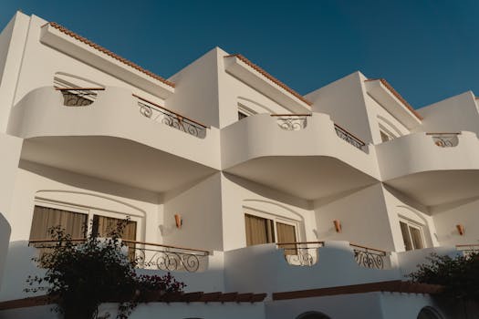 Elegant white Mediterranean building with ornate balconies under a clear blue sky.