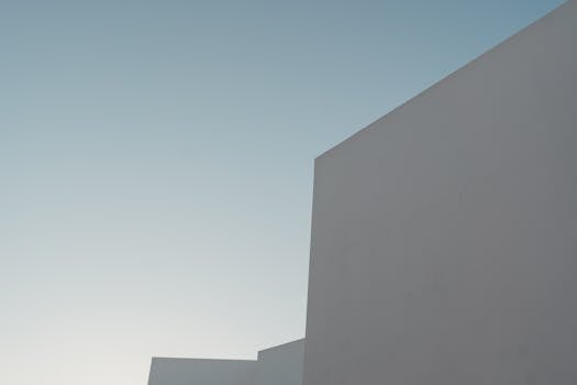 A minimalist view of a modern building's facade under a clear blue sky.