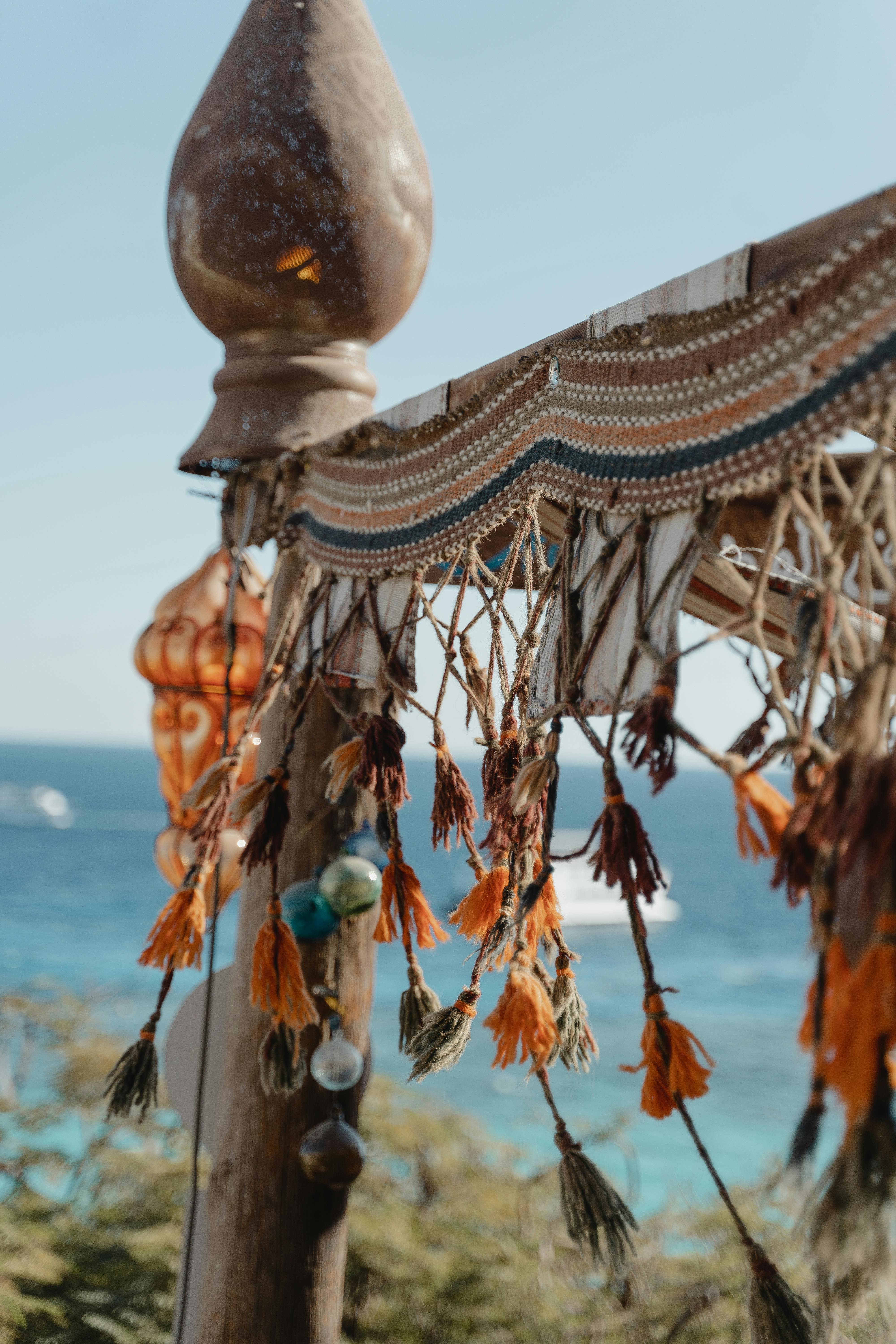 Close-up of bohemian macrame decor with tassels by the ocean, evoking a relaxed summer vibe.