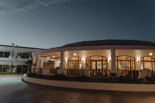 A beautifully illuminated restaurant exterior at dusk, showcasing its inviting architecture and warm lighting.