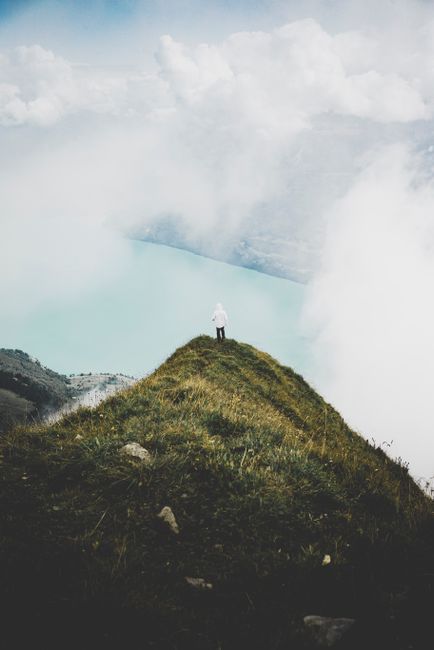 Person standing on a grassy cliff overlooking a misty lake in Brienz, Switzerland.