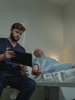 Doctor attending to a patient with an IV and nasal cannula in a hospital room.