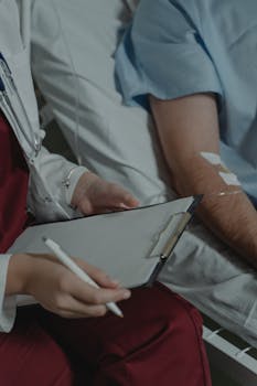 A doctor taking notes while sitting beside a patient in a hospital bed