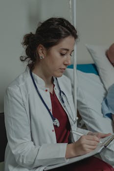 Professional female doctor taking notes on a clipboard in a hospital room.