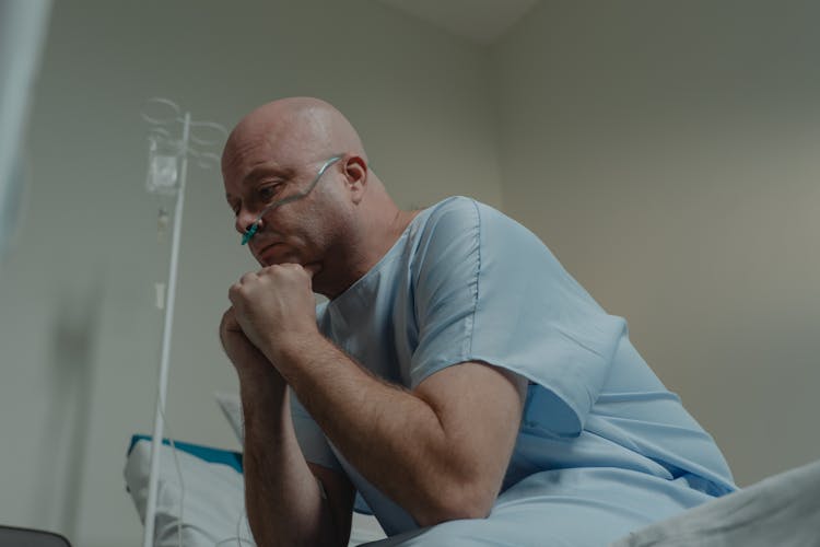 Bald Man Sitting On The Hospital Bed