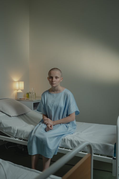 A Bald Woman Sitting on the Hospital Bed 