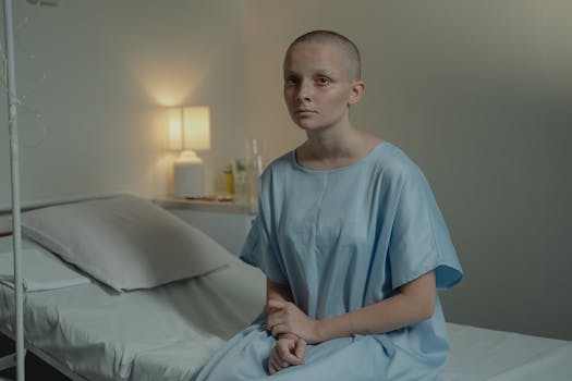 A young patient in a hospital room wearing a blue gown, conveying a calm mood.