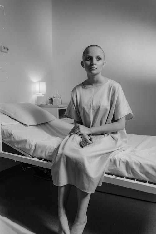 Grayscale Photo of a Girl Sitting on the Hospital Bed