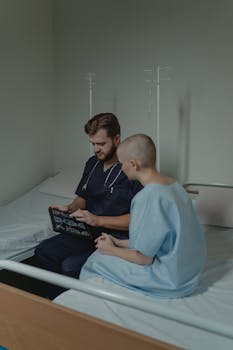 Doctor and patient in hospital room discussing CT scan results on a digital tablet.