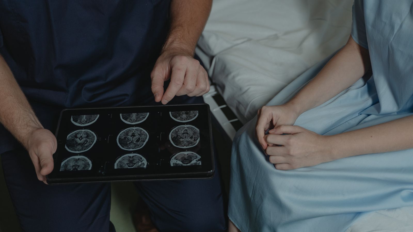 A doctor shows and explains brain scan images to a patient in a medical setting.