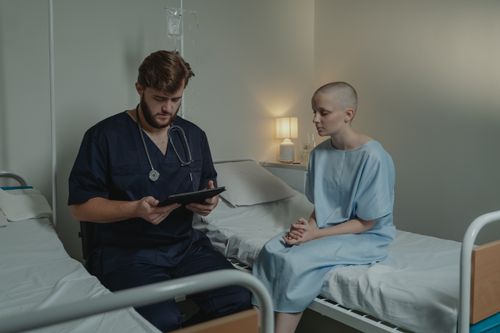 Free A doctor consulting a bald patient using a digital tablet in a hospital room. Stock Photo