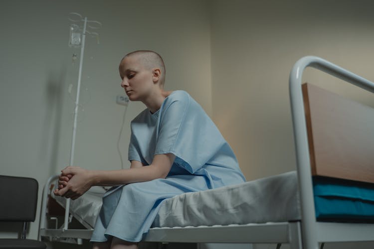 A Bald Girl Sitting On The Hospital Bed