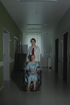 A doctor pushes a patient in a wheelchair down a hospital corridor, highlighting healthcare support.
