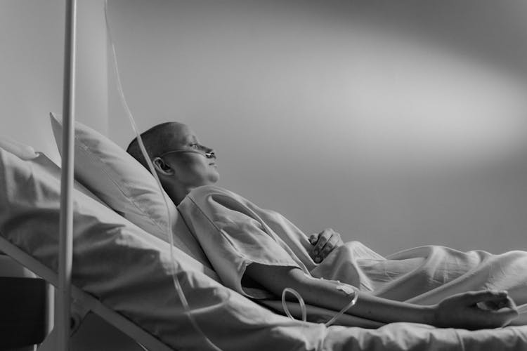 Grayscale Photo Of A Woman Lying On Hospital Bed