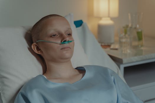 A woman in a hospital bed wearing an oxygen tube, expressing a calm yet serious demeanor.