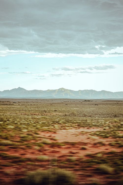 Free Vast prairie landscape featuring distant mountains and a cloudy sky. Ideal for travel and nature themes. Stock Photo