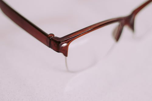 Free Brown Framed Glasses on White Surface Stock Photo