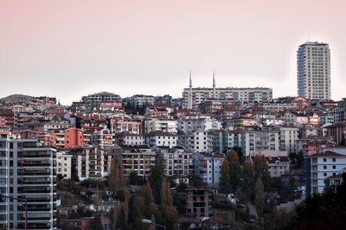 Free View of an urban skyline featuring residential buildings and a skyscraper at twilight. Stock Photo