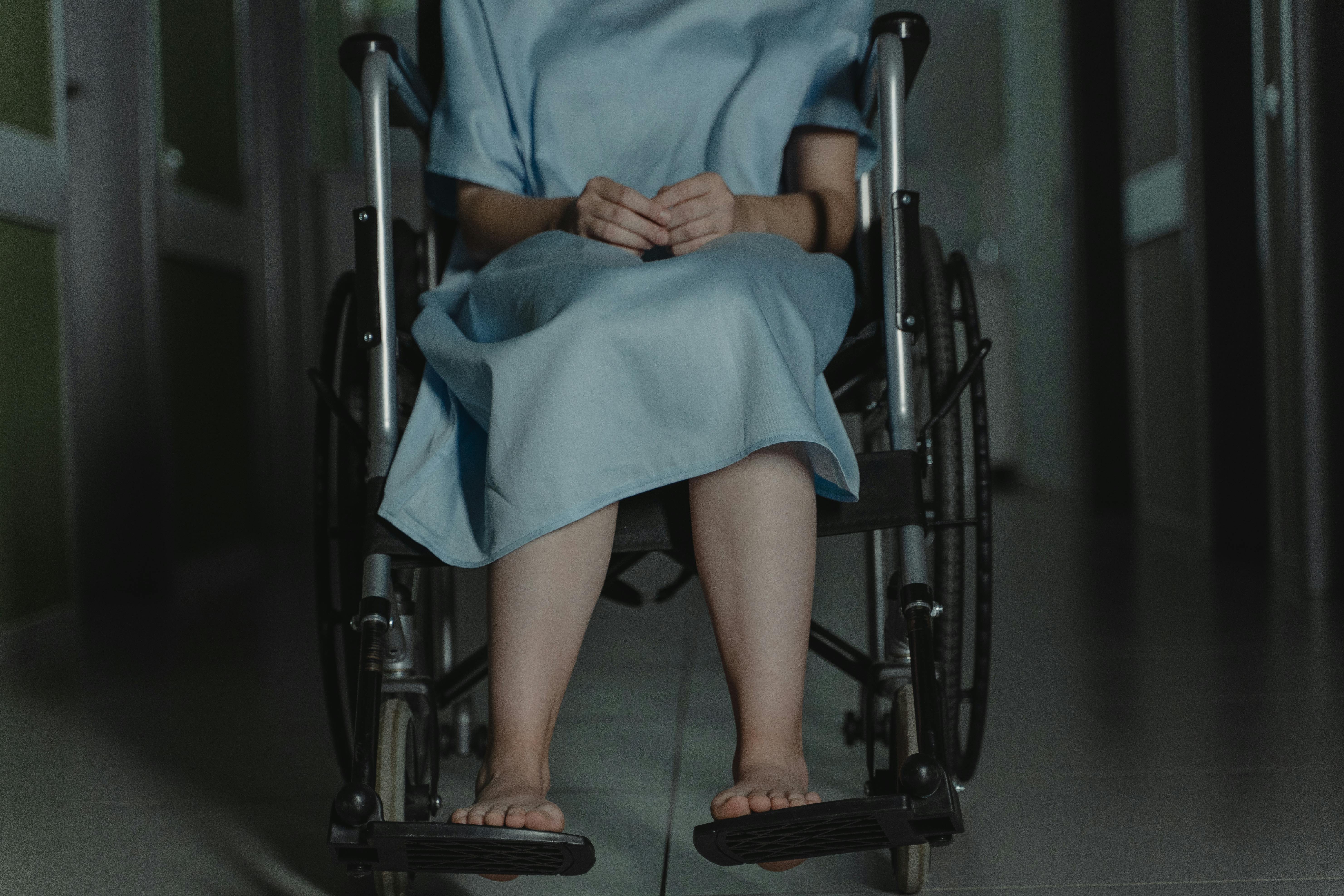 A woman in blue robe sitting on black wheelchair.  Photo: Pexels