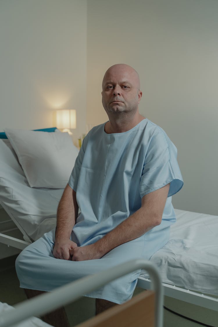 Bald Man Sitting On Hospital Bed