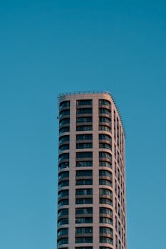 Elegant high-rise building photographed from below with a clear blue sky backdrop.