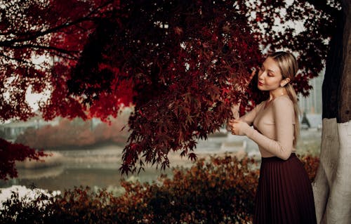 Woman touching bright red leaves of maple