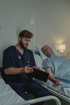 A doctor in a scrub suit caring for a patient in a hospital bed.