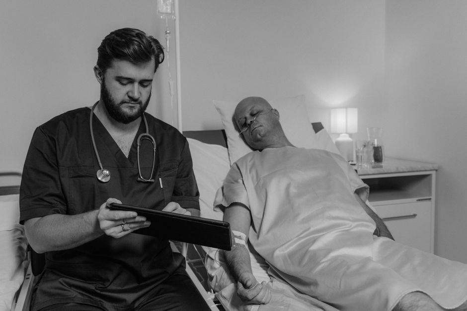 Doctor reviewing patient's data on a tablet in a hospital room.