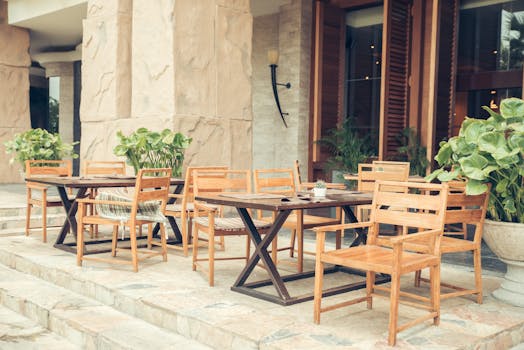 户外咖啡厅区配有木制桌椅，点缀着郁郁葱葱的绿植，显得格外优雅