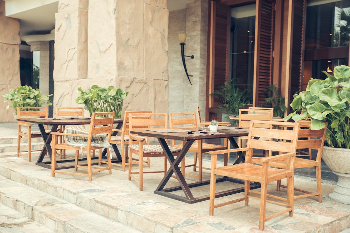 Two Sets of Brown Wooden Table and Chairs Outside Store