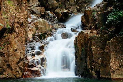 A beautiful waterfall flowing over rocks in a tranquil, natural setting, creating a serene atmosphere.