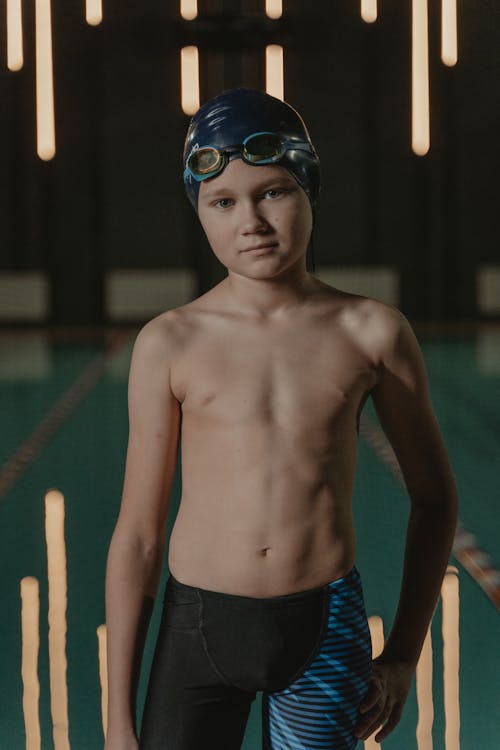 A Shirtless Boy Wearing a Swimming Cap and Goggles on His Head