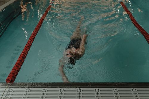 Free Swimmer performing backstroke in an indoor pool, showcasing professional swim technique. Stock Photo