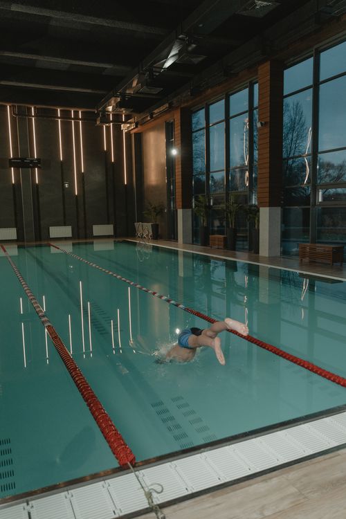 Free Diver midair in an indoor swimming pool, showcasing action and athleticism. Stock Photo