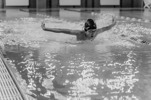 Grayscale Photo of a Boy Swimming on a Pool