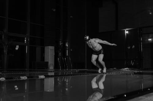 Grayscale Photo of a Man Diving on a Pool