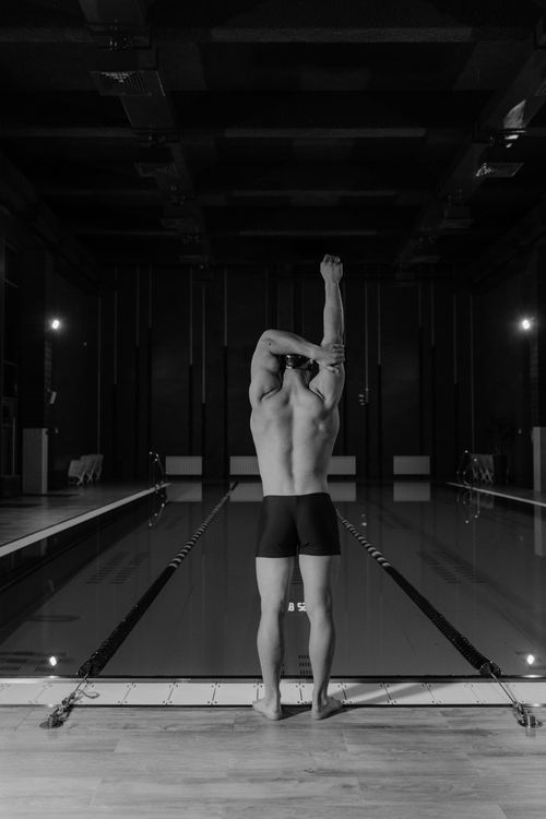 Free Male swimmer stretching at indoor pool, black and white view. Stock Photo