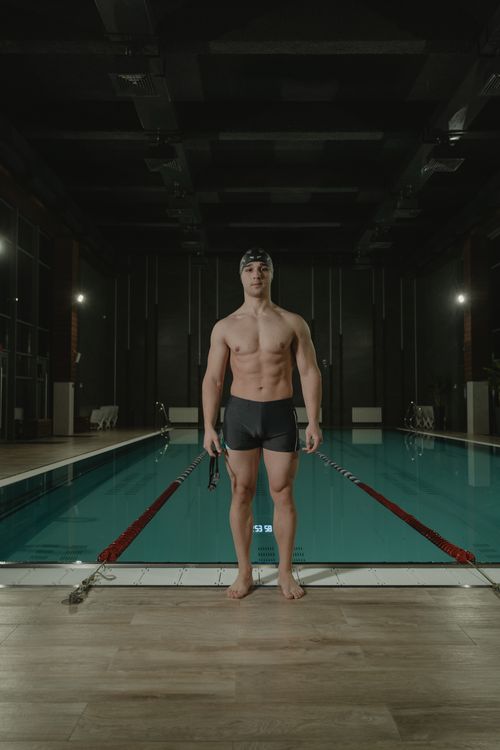 Free Athlete in black swim shorts stands poolside ready for swim. Stock Photo
