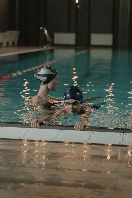 Free Two adults practicing swimming in an indoor pool, emphasizing fitness and training. Stock Photo