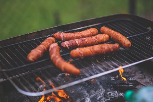 Free Delicious sausages sizzling on a charcoal grill, perfect for summer barbecues. Stock Photo