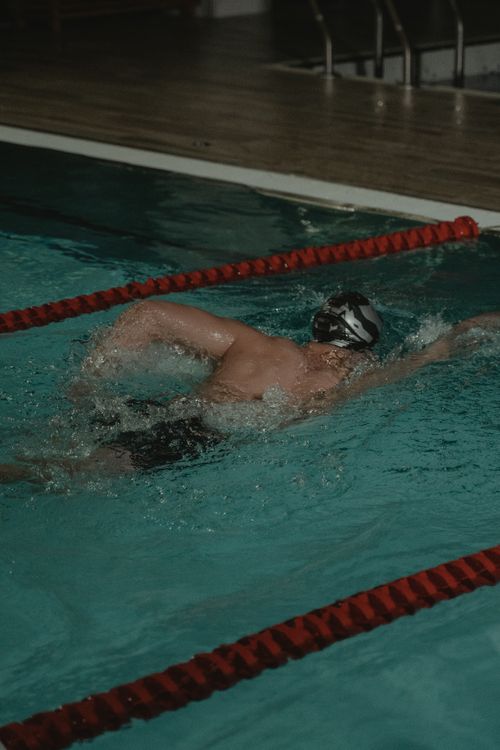 Free A competitive swimmer engages in freestyle stroke in an indoor swimming pool during daytime. Stock Photo