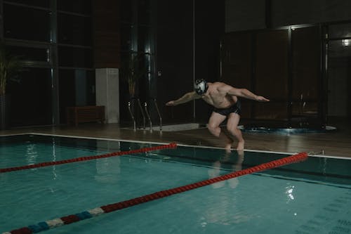 Man in Black Swimming Trunks Jumping on Swimming Pool