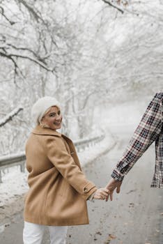 Couple enjoying a romantic walk during winter, surrounded by snow-covered trees.