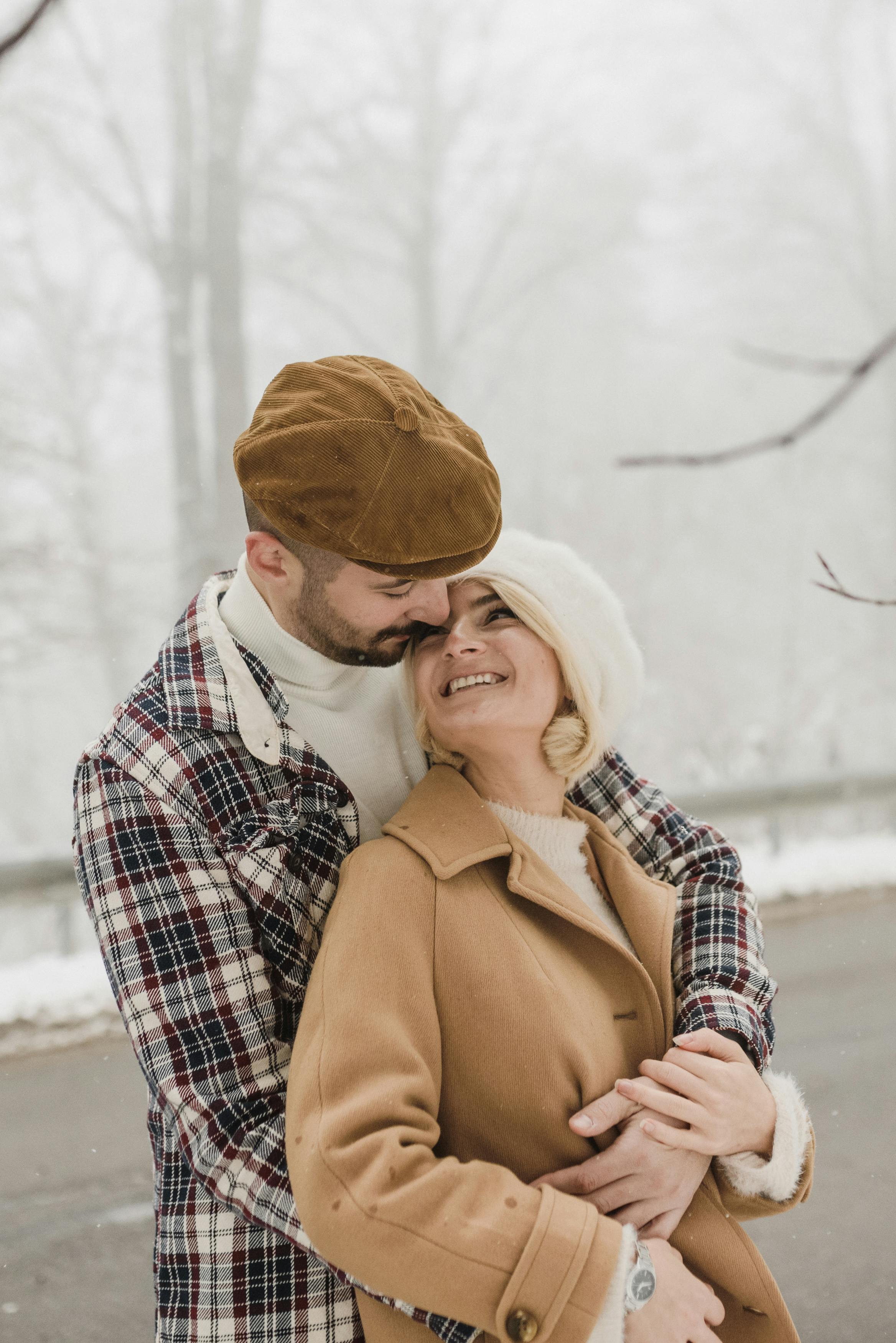 Free Photo of a Man with a Beret Cap Hugging a Woman in a Brown Coat Stock Photo