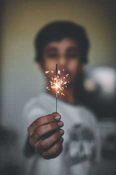 A child holding a lit sparkler, creating a festive and joyful atmosphere.